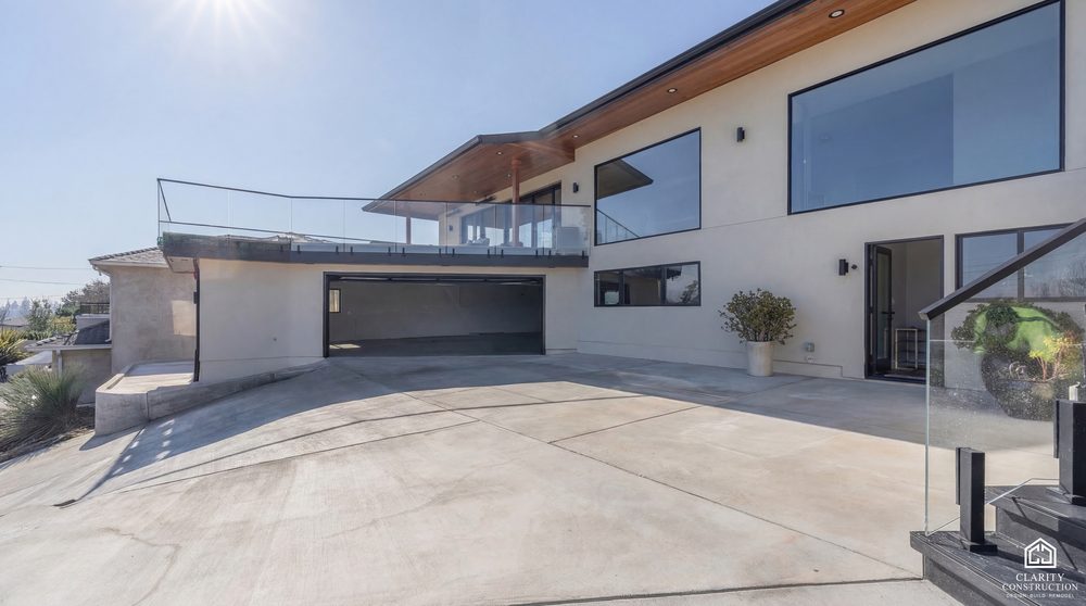 Hillside home with a new driveway, glass railing and a deck cantilevered over the slope