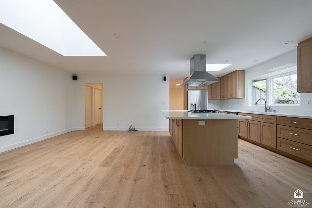 Sunlit open plan main floor of a whole home renovation, white oak floors running from the island kitchen to the living room